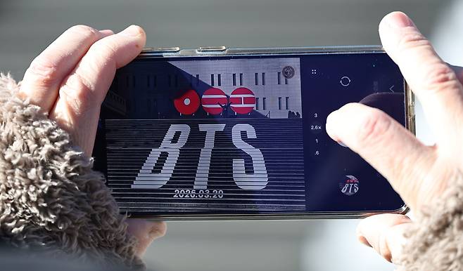 서울 종로구 세종문화회관 계단에서 한 관광객이 그룹 방탄소년단(BTS)의 컴백을 알리는 홍보물을 기념촬영하고 있다. [연합]