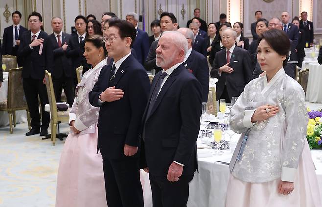 이재명 대통령이 23일 청와대에서 열린 루이스 이나시우 룰라 다시우바 브라질 대통령 국빈 방한 환영 만찬에서 국기에 경례하고 있다.      왼쪽부터 다시우바 여사, 이재명 대통령, 루이스 이나시우 룰라 다시우바 브라질 대통령, 김혜경 여사. [연합]