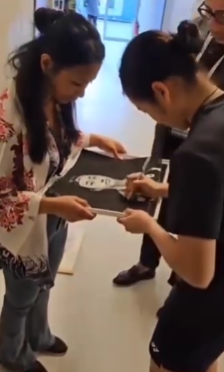 ▲ 선수 출신 작가 라자피니마나나가 안세영 초상화가 불우한 아이들을 돕는 자선단체인 솔리배드에 기증될 예정이라 설명하자 친필 사인을 하는 안세영의 모습.