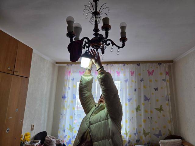 17일 안나가 키이우 아파트에서 정전에도 4시간 불을 밝힐 수 있는 휴대용 조명을 방에 걸고 있다. 키이우=정승임 특파원