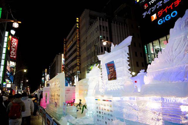 삿포로 눈 축제 스스키노 구역의 얼음조각이 주위의 네온사인이 비치고 있다.