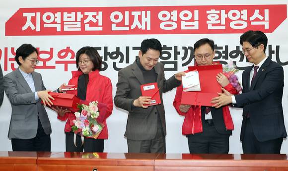 국민의힘 장동혁 대표가 25일 국회에서 열린 지역발전 인재영입 환영식에서 손정화 삼일회계법인 이사(왼쪽 두 번째), 정진우 현대엔지니어링 에너지영업팀 책임매니저(오른쪽 두 번째)에게 '시크릿 박스'를 전달한 뒤 내용물을 설명하고 있다. '시크릿 박스'에는 국민 목소리를 듣고 기록하는 경청노트와 펜, 당헌당규집과 당 뱃지, 국민과 함께 눈비 맞으며 국민 일상 챙겨달라는 의미의 우산과 시계가 들어있다. 2026.2.25 [사진=연합뉴스]