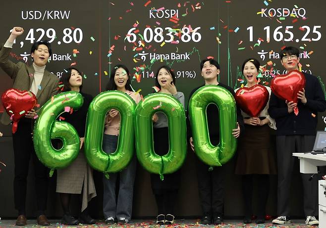 코스피가 사상 처음으로 6,000을 돌파해 거래를 마친 25일 서울 중구 하나은행 딜링룸에서 딜러들이 기념 세리머니를 하고 있다. 연합뉴스