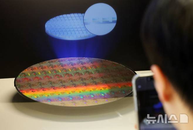 [서울=뉴시스] 조성우 기자 = 11일 오후 서울 강남구 코엑스에서 열린 세미콘 코리아 2026를 찾은 한 관람객이 반도체 웨이퍼 사진을 찍고 있다. 2026.02.11. xconfind@newsis.com