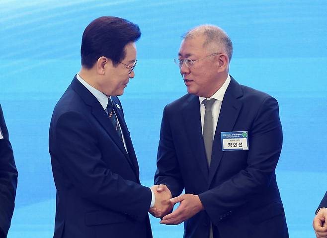 이재명 대통령이 27일 전북 군산새만금컨벤션센터에서 열린 새만금 로봇,수소,AI 시티 투자협약식에서 기념촬영을 마친 뒤 정의선 현대차그룹 회장과 악수하고 있다.연합뉴스