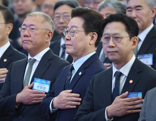 정의선(왼쪽부터) 현대차그룹 회장, 이재명 대통령, 배경훈 부총리 겸 과기부 장관이 27일 전북 군산새만금컨벤션센터에서 열린 새만금 로봇·수소·AI 시티 투자협약식에서 국민의례를 하고 있다. [연합]