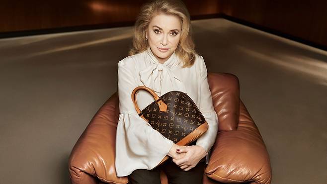 프랑스 배우 카트린느 드뇌브가 루이 비통 알마 백을 안고 카메라를 응시하고 있다. 사진 루이 비통