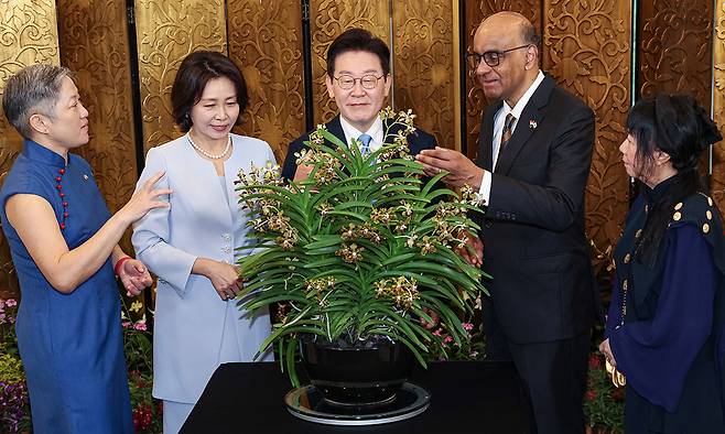 ‘이재명 김혜경 난’ 싱가포르를 국빈 방문 중인 이재명 대통령과 김혜경 여사가 2일(현지시간) 싱가포르 외교부에서 타르만 샨무가라트남 대통령(오른쪽 두번째), 제인 이토기 샨무가라트남 여사(오른쪽)와 회담에 앞서 진행된 난초 명명식에서 싱가포르의 국화인 난초에 대한 설명을 듣고 있다. 난초 명명식은 외국 정상 등 주요 인사의 싱가포르 방문 시 난초 교배종에 방문 인사의 이름을 붙이는 행사다. 싱가포르=뉴스1