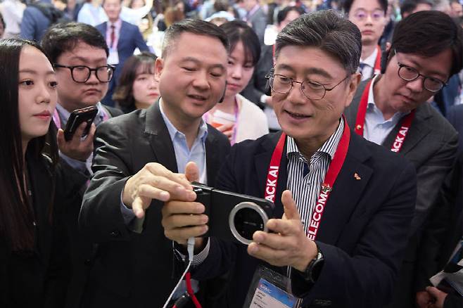 2일(현지시간) 스페인 바르셀로나에서 개막한 MWC26에서 정재헌(오른쪽) SKT CEO가 샤오미 부스를 둘러보면서 라이카와 협업한 샤오미17 울트라를 작동해보고 있다.(사진=SKT)