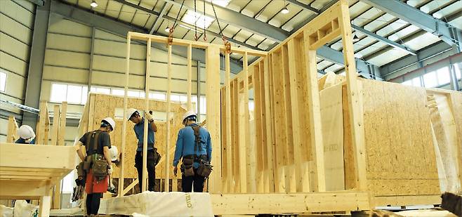 충남 당진의 GS건설 모듈러 주택 ‘자이가이스트’ 제조 공장에서 나무로 주택 골조 만드는 작업이 진행 중이다. 모듈러 주택은 벽·지붕 등 건물의 주요 구성품(모듈)을 공장에서 사전 제작하고, 실제 건물이 들어설 현장에선 각 모듈을 가져다 조립·설치하는 방식으로 공사가 이뤄진다. 작은 사진은 모듈 여러 개를 연결해 완성한 집의 내부 모습. 벽에서 천장으로 이어지는 선이 모듈이 결합한 부위다./GS건설