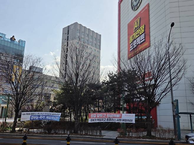 홈플러스 강동점 외벽에 노조 현수막이 내걸려 있다. "MBK 먹튀로 홈플러스 무너지고 지역경제 파탄난다", "정부가 책임지고 홈플러스 사태 해결하라" 등의 문구가 적혀 있다. (사진=한전진 기자)