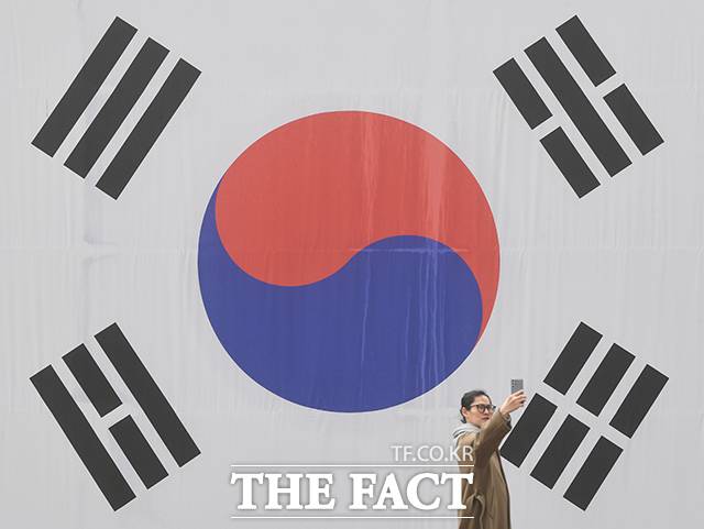 한 시민이 6일 오후 서울 서대문구 서대문형무소에 걸린 태극기를 배경으로 사진을 찍고 있다. /박상민 기자