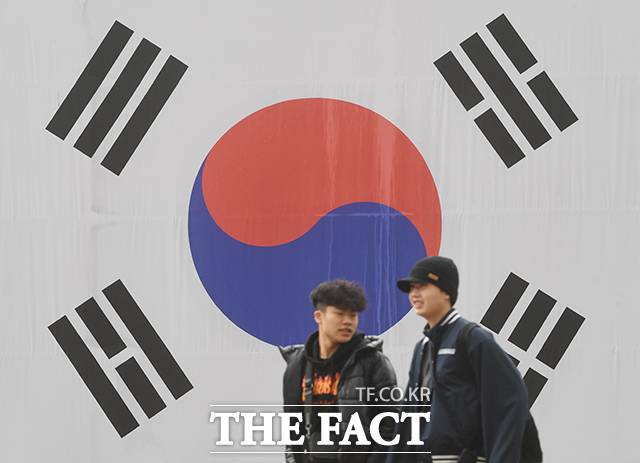 관광객들이 서울 서대문구 서대문형무소에서 건물에 걸린 태극기 앞을 지나고 있다.