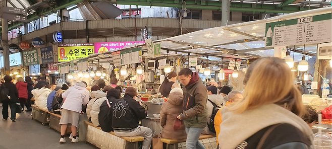 지난 6일 오후 서울 종로구 광장시장에서 외국인 관광객들이 먹거리 노점 앞에 줄지어 앉아 식사를 하고 있다. 오는 21일 광화문에서 열리는 방탄소년단(BTS) 공연을 앞두고 도심 관광 상권에 외국인 방문객이 늘어나는 추세다. 사진=최승한 기자