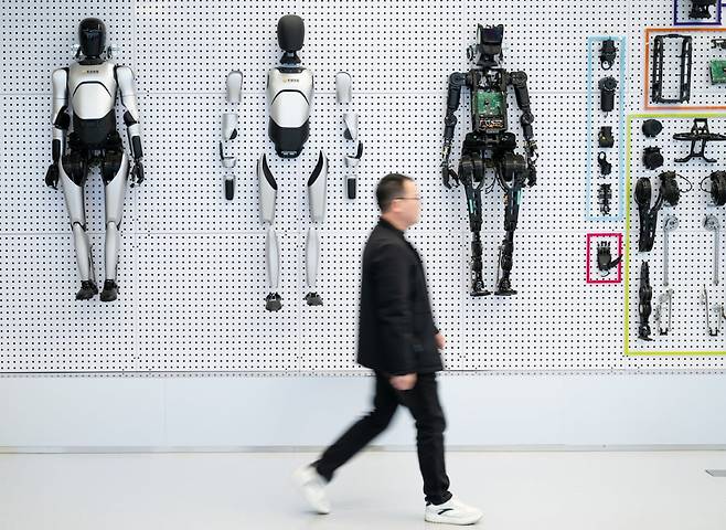 중국 중부 후베이성 우한의 동후 고신기술개발구 내 휴머노이드 로봇 혁신 센터에서 한 방문객이 전시된 로봇과 부품들 사이를 지나가고 있다. 사진=연합신화