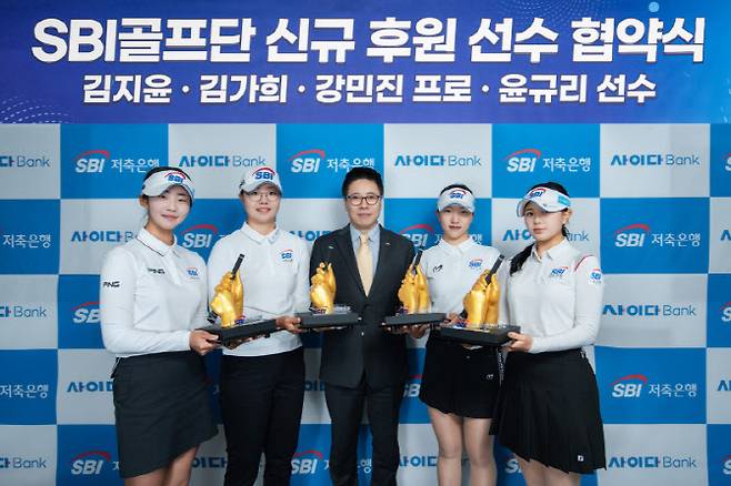 김문석 SBI저축은행 대표(가운데)와 2026시즌 골프단 신규 후원 선수들이 시그니처 그립 스컬프처를 들고 기념촬영을 하고 있다. 왼쪽부터 김지윤, 김가희, 김문석 대표이사, 강민진, 윤규리.(사진=SBI저축은행 골프단)