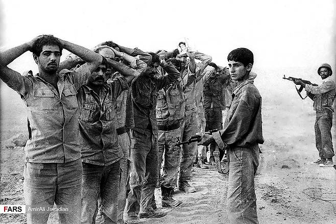 이란 소년병이 1982년 이란-이라크 전쟁 중 이라크 포로들을 감시하고 있다. 사진 위키피디아
