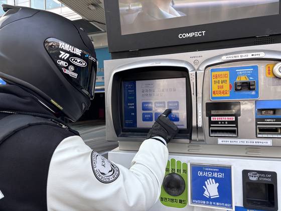 A motorcycle driver presses a panel button to refuel a motorcycle at a self-service gas station in Seongbuk District, central Seoul, on March 9. [KWAK JOO-YOUNG]