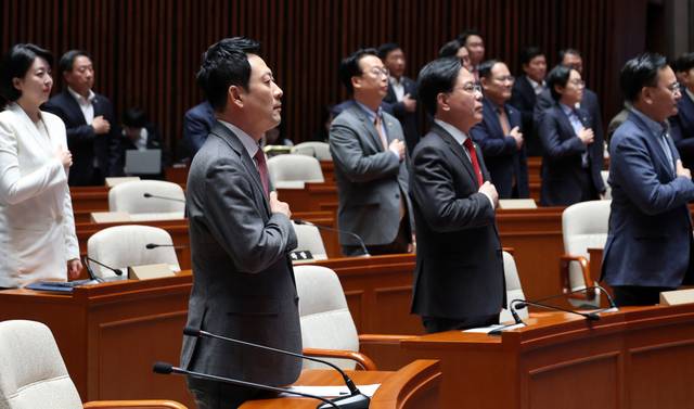장동혁 대표와 송언석 원내대표를 비롯한 국민의힘 의원들이 9일 국회에서 열린 긴급 의원총회에서 국기에 경례하고 있다. 연합뉴스