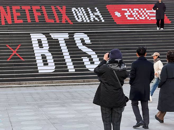 A tourist takes a photo of an advertisement for a BTS concert installed on the steps of the Sejong Center next to Gwanghwamun Square in Jongno District, central Seoul, on March 8. [IM SOUNG-BIN]