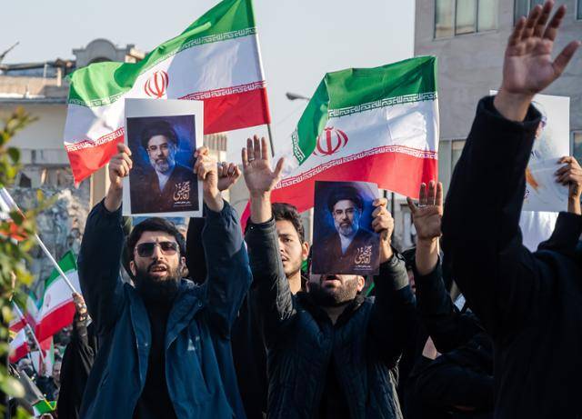 9일 이란 테헤란 혁명거리에서 열린 집회에서 남성들이 새 최고지도자 모즈타바 하메네이의 초상화를 들어 보이고 있다. UPI 연합뉴스