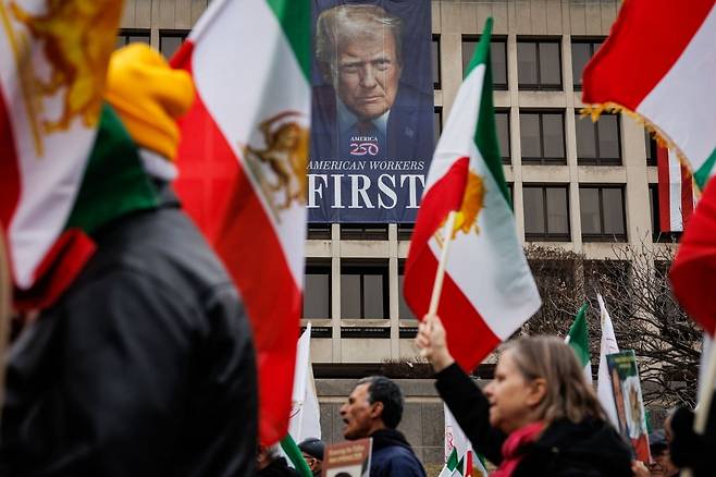 지난 7일(현지시간) 미국 워싱턴 DC에서 미국과 이스라엘의 이란 공습을 지지하는 시위대가 미국 노동부 청사에 걸린 도널드 트럼프 미국 대통령의 초상화가 그려진 배너 앞을 지나가고 있다. 사진=게티이미지