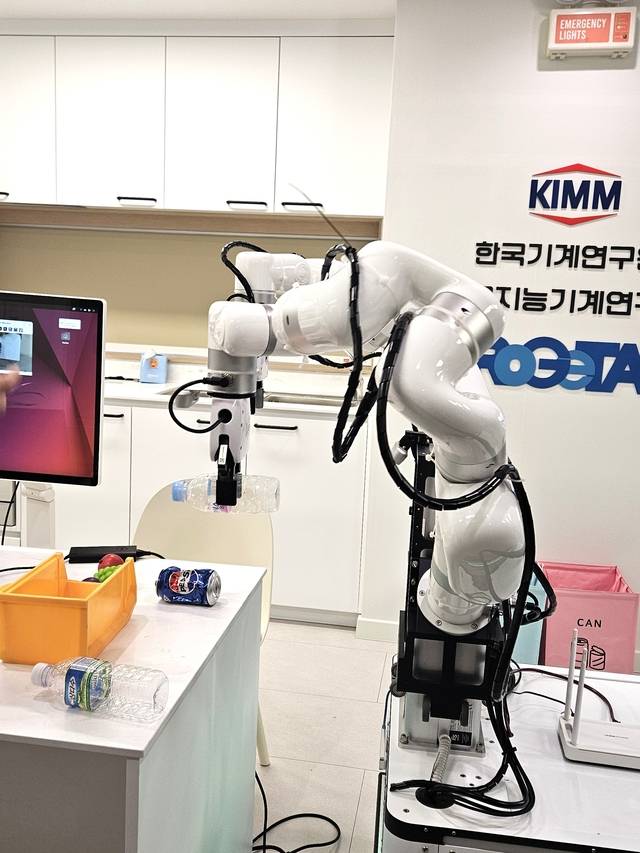 AI작업 로봇이 플라스틱 생수병을 들어 분리수거함으로 이동하고 있다. 사진=이준기기자.