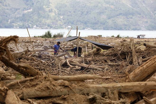 지난 2일 인도네시아 아체주 중부 토웨란 마을에서 주민들이 홍수와 산사태로 떠내려온 통나무들을 치우며 마을을 정비하고 있다. 탄소 배출이 가져올 폐해를 미리 계산해 비용을 부과하면 이런 일을 막을 수 있을까. EPA 연합뉴스