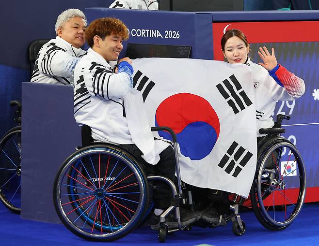 11일(현지시간) 이탈리아 코르티나 컬링 올림픽 스타디움에서 열린 2026 밀라노·코르티나담페초 동계 패럴림픽 휠체어컬링 믹스더블 결승 대한민국과 중국의 경기. 은메달을 차지한 이용석과 백혜진이 카메라를 향해 인사하고 있다. [연합]