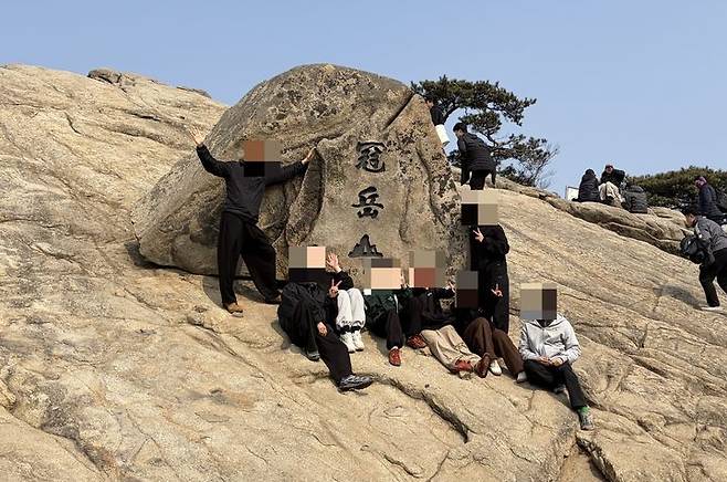 [서울=뉴시스] 김건민 인턴기자 = 젊은 등산객들이 관악산 정상에 위치한 비석 앞에서 단체 사진을 찍고 있다. 비석에는 '관악산'이라는 한자가 새겨져 있다. 2026.03.11. *재판매 및 DB 금지