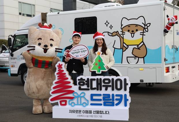 현대위아 직원들이 지난해 12월 경남 창원 현대위아 본사 앞에서 지역 사회복지기관 10곳에 선물할 ‘현대위아 드림카’와 함께 기념 사진을 찍고 있다. 사진 제공=현대위아