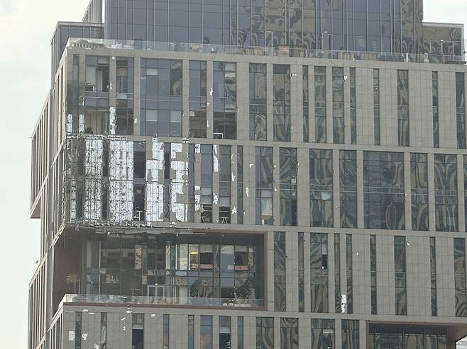 13일 아랍에미리트 두바이에서 요격 과정에서 발생한 파편에 외벽 손상을 입은 두바이 국제금융센터(DIFC) 내 건물의 모습이 보인다. 사진은 휴대전화로 촬영됨. 로이터 연합뉴스