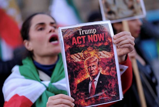 지난 2월 스페인 바르셀로나에서 이란 반정부 시위대가 도널드 트럼프 미국 대통령과 팔라비 왕조 시절 이란 국기, "트럼프 지금 행동하라"는 구호가 있는 선전 포스터를 들고 시위를 하고 있다. 로이터=연합뉴스