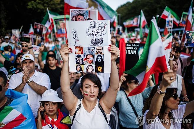 '히잡 의문사 1주기' 희생자 사진 들어 올린 독일 시위대 히잡을 쓰지 않았다는 이유로 경찰 조사를 받다 의문사한 이란 여성 마흐사 아미니(사망 당시 22세)의1주기를 맞아 2023년 9월 16일(현지 시각) 독일 베를린에서 시위가 열리고 있다. 한 시위자는 아미니를 비롯한 희생자들의 사진이 인쇄된 종이를 들고 있다. 이날 이란 각지와 세계 곳곳에서 아미니를 추모하는 시위가 이어졌다.
[EPA 사진]