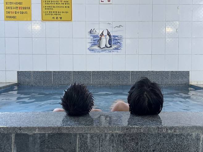 김성진씨의 두 아들이  충남 홍성에 있는 '서문탕'의 냉탕에 들어가 펭귄이 그려져 있는 벽화를 바라보고 있다. 김씨 제공.