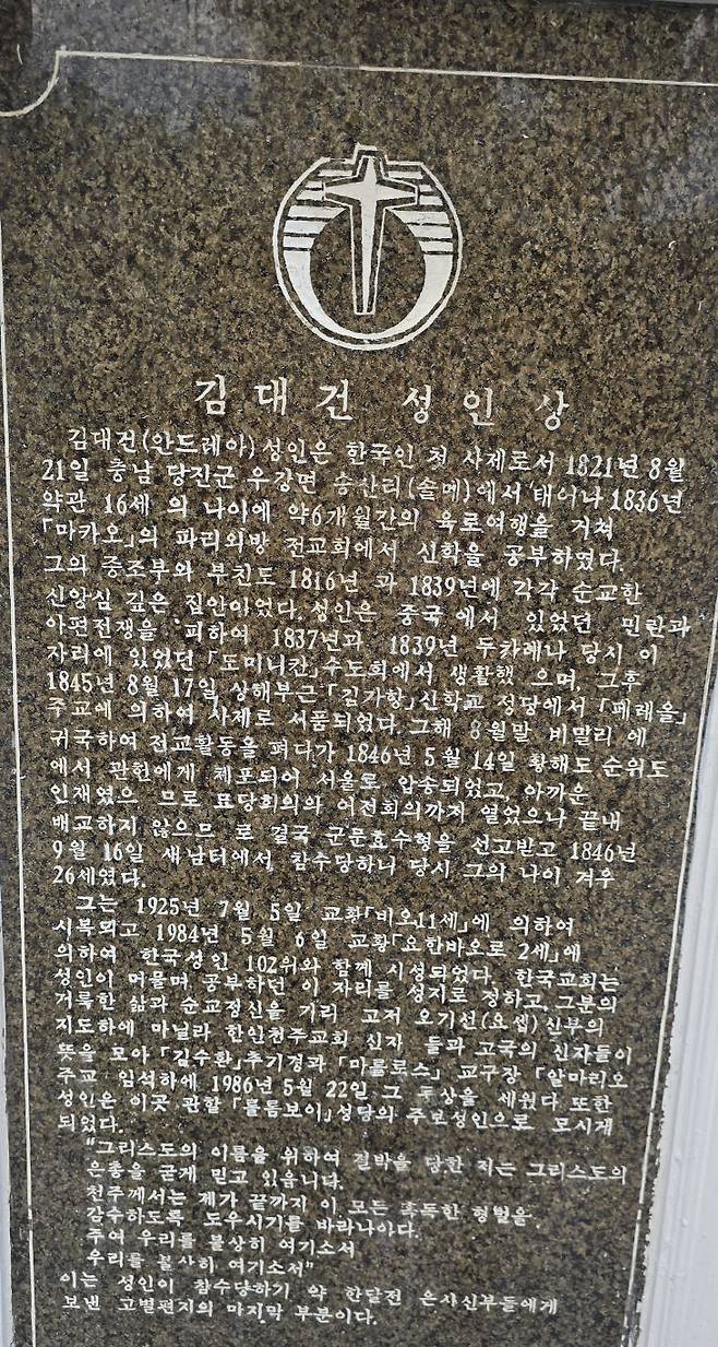 김정수 신부가 김 신부 대부인 오기선 요셉 신부 흉상 앞에서 오기선 요셉 신부에 대해 설명하고 있다.