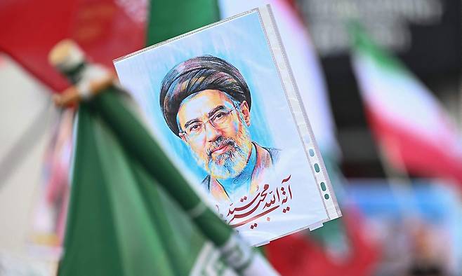 14일(현지시간) 파리에서 중동 전쟁 반대 행진과 인종차별, 파시즘, 국가 폭력에 반대하는 집회가 열린 가운데 한 시위자가 이란의 새 최고지도자 모즈타바 하메네이의&nbsp;초상화를 들고 있다. AFP연합뉴스