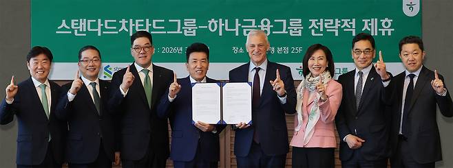 함영주(왼쪽 네 번째) 하나금융그룹 회장과 빌 윈터스(왼쪽 다섯 번째) 스탠다드차타드그룹 회장(사진 왼쪽에서 다섯번째)이 13일 서울 중구 하나은행 본점에서 하나금융그룹 및 스탠다드차타드그룹 임직원들과 함께 협약서를 들고 기념촬영을 하고 있다. 사진 제공=하나금융