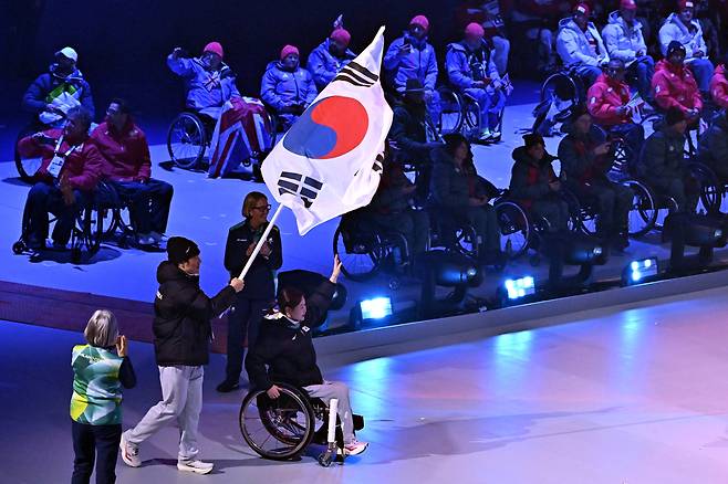 휠체어컬링 백혜진과 스노보드 이제혁이 15일(현지시간) 이탈리아 코르티나담페초 컬링 올림픽 스타디움에서 열린  2026 밀라노 코르티나 패럴림픽 폐막식에서 태극기를 들고 입장하고 있다.  코르티나 | 사진공동취재단