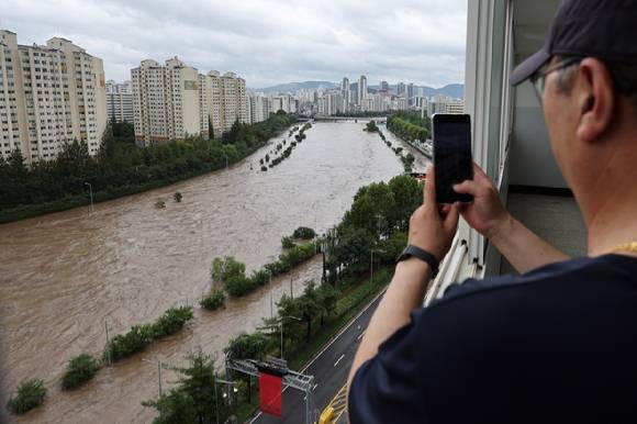 집중호우가 내린 지난해 8월 13일 한 시민이 범람한 중랑천과 통제된 동부간선도로를 사진으로 찍고 있다. [사진=연합뉴스]