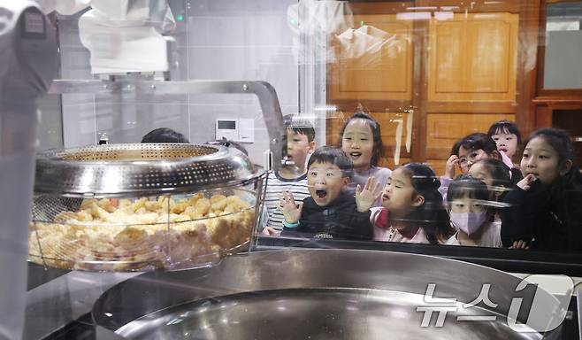 18일 경기 수원시 장안구 대평초등학교 내 위치한 거점형 학교급식 튀김 지원실에서 1학년 학생들이 튀김 조리 로봇이 직접 가동되는 현장을 보고 있다. 2026.3.18 ⓒ 뉴스1 김영운 기자