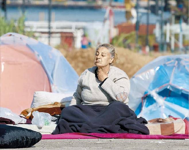 레바논 피란민 83만명 넘어  16일 공습을 피해 레바논 베이루트로 대피한 여성이 텐트 옆에 앉아있다. 레바논 피란민은 83만명을 넘었다./EPA 연합뉴스