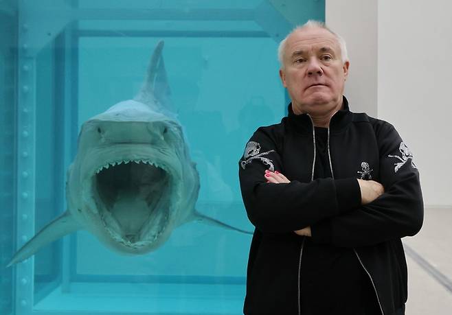 영국 작가 데이미언 허스트가 18일 서울 종로구 국립현대미술관에서 열린 ‘진실은 없어 그러나 모든 것은 가능하지’ 개인전에 전시된 대표작 ‘살아있는 자의 마음 속 죽음의 물리적 불가능성’ 앞에서 포즈를 취하고 있다. <연합뉴스>