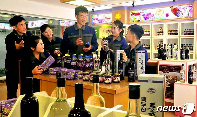 (평양 노동신문=뉴스1) = '백두산 들쭉술'을 들고 있는 북한 주민들의 모습. 백두산 들쭉술은 백두산에서 자라는 진달래과 들쭉나무 열매인 들쭉을 주원료로 해 만든 술로 알려져 있다. [국내에서만 사용가능. 재배포 금지. For Use Only in the Republic of Korea. Redistribution Prohibited] rodongphoto@news1.kr