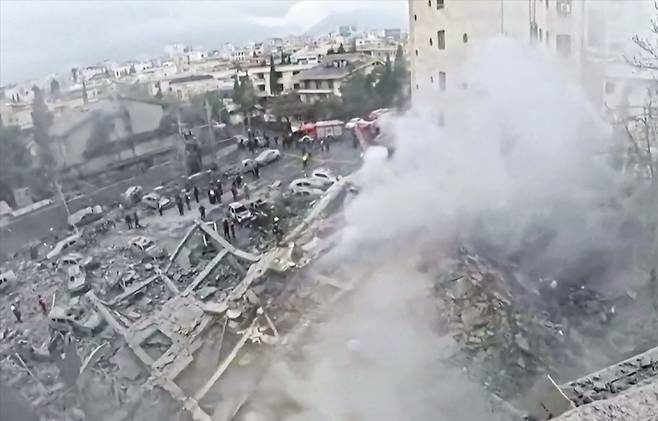 폭격에 무너진 이란 주택가  18일 이란 적신월사가 공개한 미국·이스라엘 공습 현장 사진. 폭격 직후 연기가 피아오르는 가운데 부서진 건물 잔해 주변에 구조요원으로 보이는 사람들이 모여있다. 적신월사는 촬영지점의 구체적인 위치를 밝히지 않았다./AFP 연합뉴스