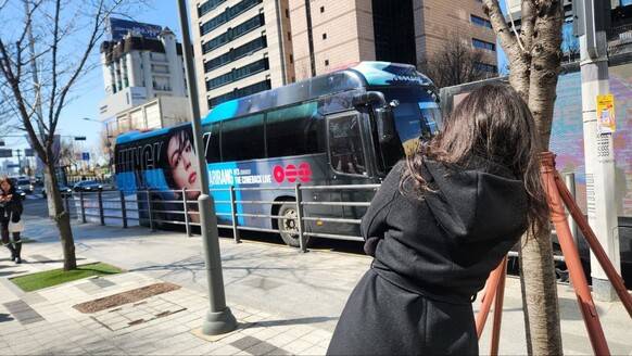 19일 낮 서울 용산구 하이브 건물 앞에서 이탈리아 출신 엘리사(34)씨가 방탄소년당(BTS) 멤버 정국의 얼굴이 새겨진 버스 사진을 찍고 있다. 장종우 기자