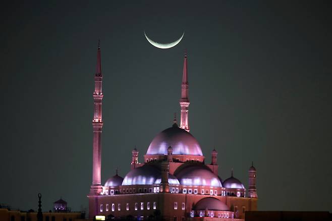라마단 시작 둘째 날인 지난달 20일 이집트 카이로의 한 모스크 위로 초승달이 떠 있다. 라마단은 이슬람력 아홉 번째 달로, 초승달 관측을 기준으로 시작해 약 29~30일간 이어진다. 이후 다시 초승달이 관측되면 라마단이 종료되고 다음 날부터 이드 알피트르가 시작된다. 라마단 시작과 종료일은 국가마다 차이가 있다. /신화 연합뉴스