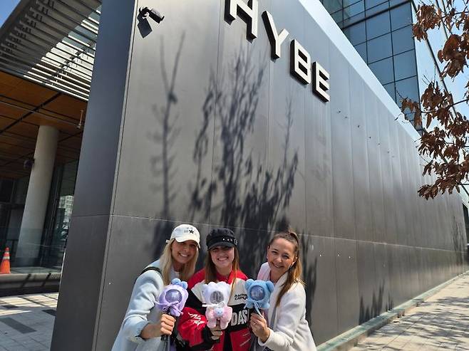 브라질에서 온 BTS 팬들이 하이브 간판 앞에서 '아미봉'을 들고 포즈를 취하고 있다.ⓒ데일리안 허찬영 기자