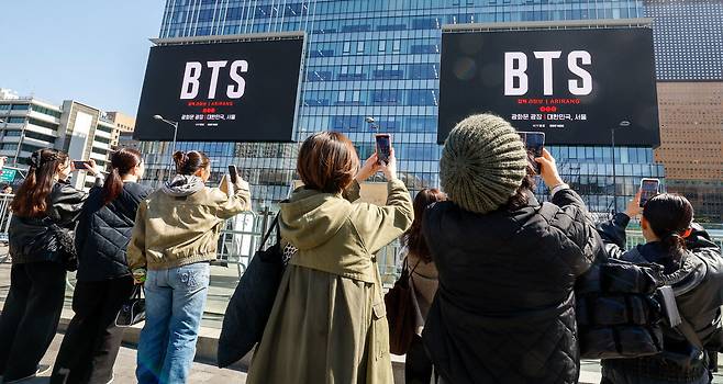 방탄소년단(BTS) 컴백 공연을 앞둔 지난 19일 서울 종로구 광화문광장 인근에서 시민과 외국인관광객들이 건물 옆에서 송출되는 공연 광고를 촬영하고 있다. 유희태 기자