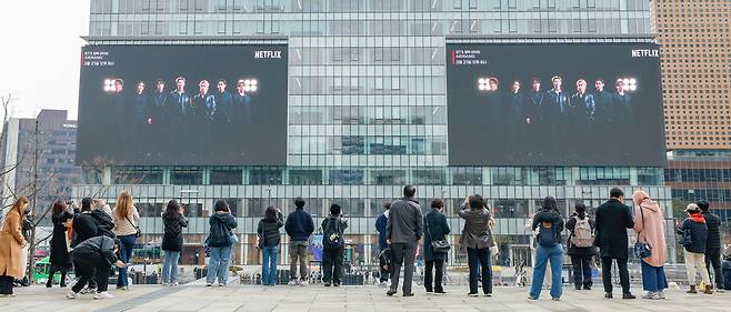 방탄소년단(BTS)의 서울 광화문광장 컴백 공연을 하루 앞둔 20일 서울 종로구 세종문화회관 계단에서 외국인 관광객들이 전광판에 송출되는 공연 광고를 기념촬영하고 있다.